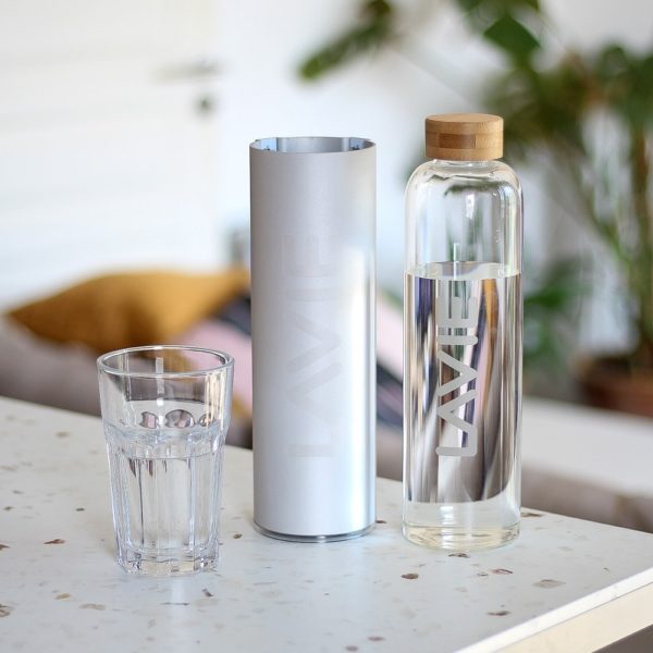 Water in a glass next to bottle and purifier