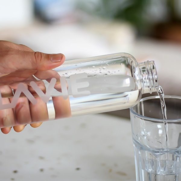 Man pouring water from glass bottle into cup